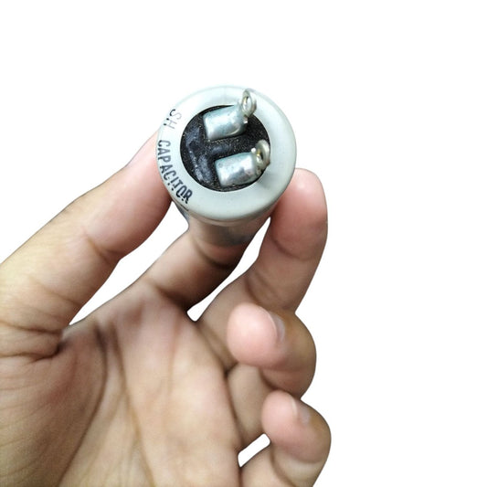 Hand holding a 400V Motor Running Capacitor for electrical circuitry applications