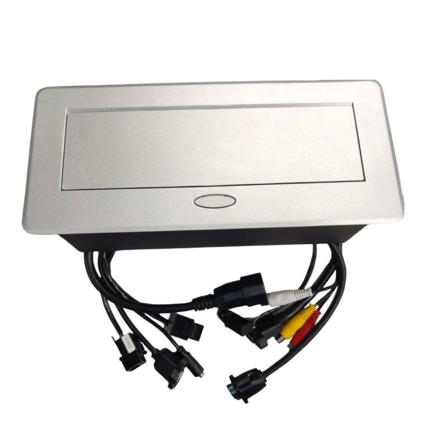 A rectangular silver metal electronic control box with a recessed front panel and a small oval mark, shown with attached black cables and multi-pin connectors, plus red, yellow, and white video-style plugs, on a plain white background.