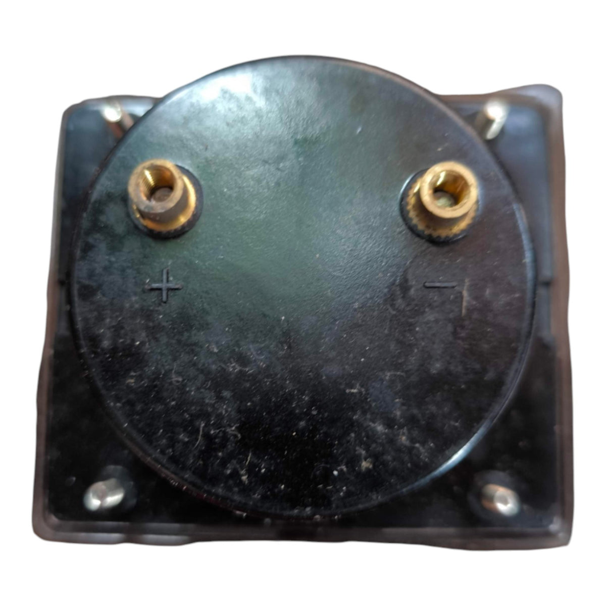 A square black electrical component or terminal block with a circular top plate, featuring two gold-colored screw terminals labeled with plus and minus signs, on a white background.