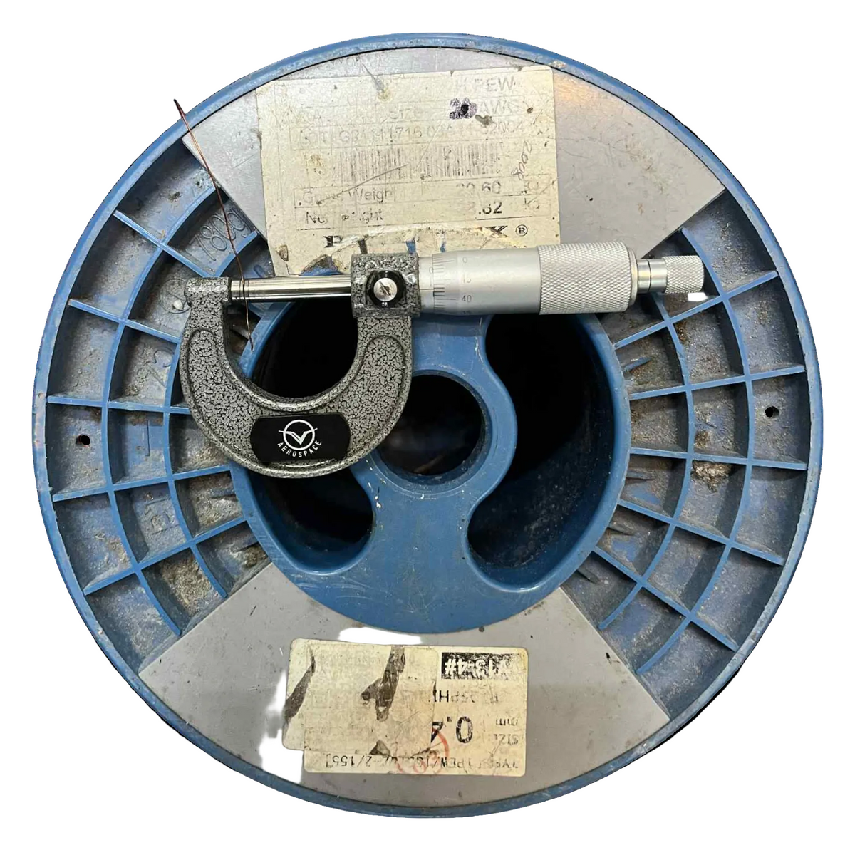 Vintage micrometer on a blue metal reel with labels on a white background