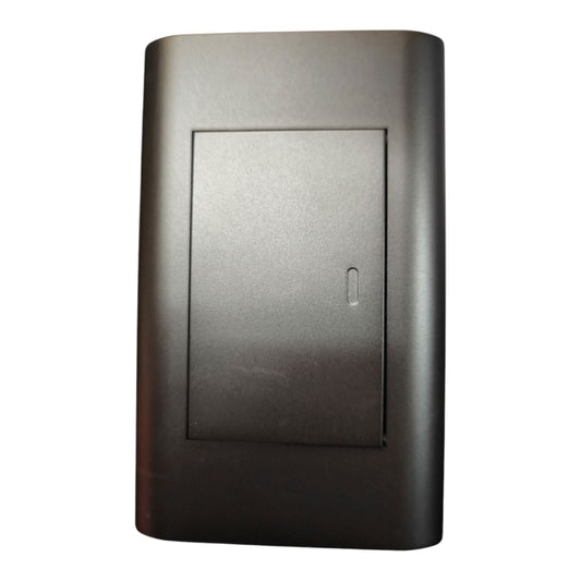A dark gray rectangular electronic module or cover with a recessed center panel and a small vertical slot, shown on a plain white background.