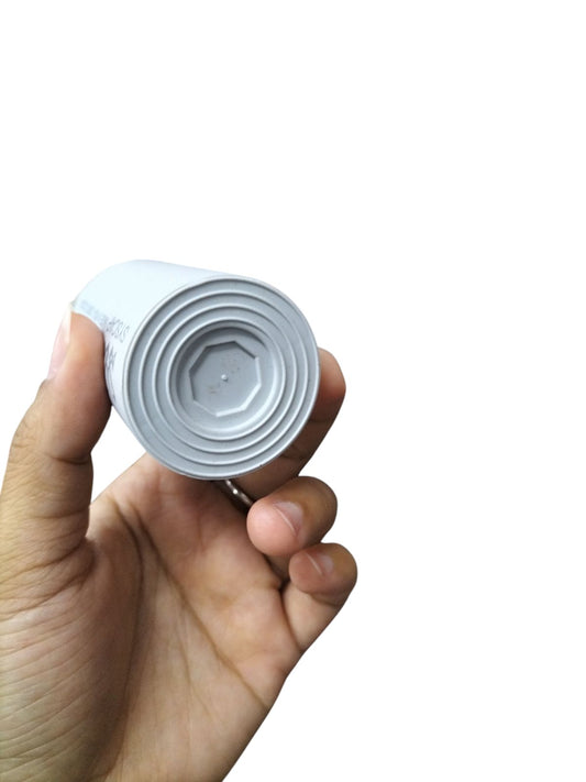 Syscap Motor Capacitor in a cylindrical design, held in hand for easy installation