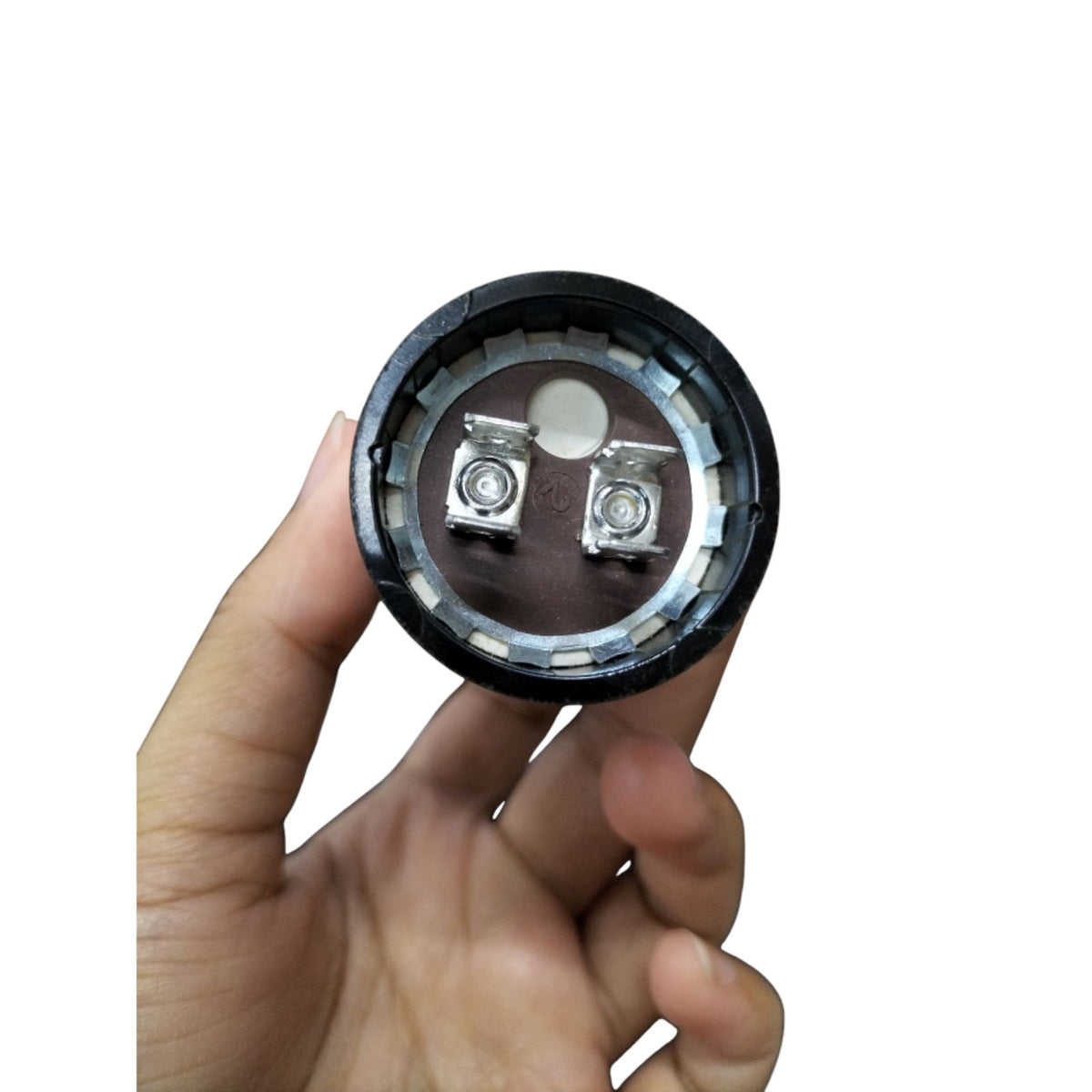 Starting Capacitor 18-22UF 250V shown in hand, featuring metallic connection terminals for electrical applications