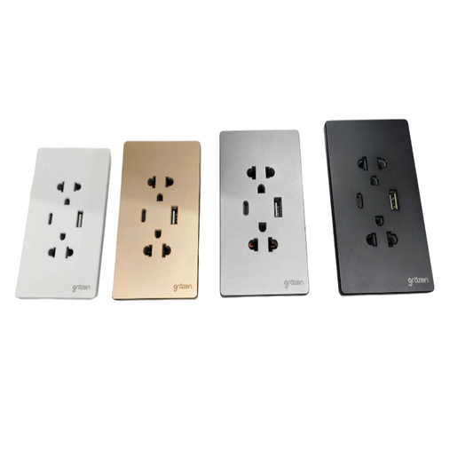 Four modern wall outlet panels with USB-A and USB-C ports, shown in white, champagne gold, silver, and black finishes on a plain white background.