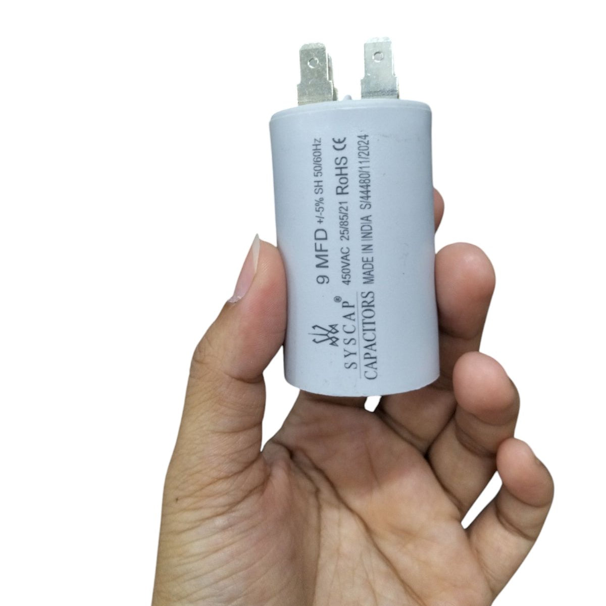 Hand holding a Syscap 9MFD 450 VAC Running Capacitor for electrical circuitry and parts