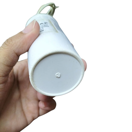 Hand holding a Syscap Running Capacitor 15uF 600V with a white casing and wire connection