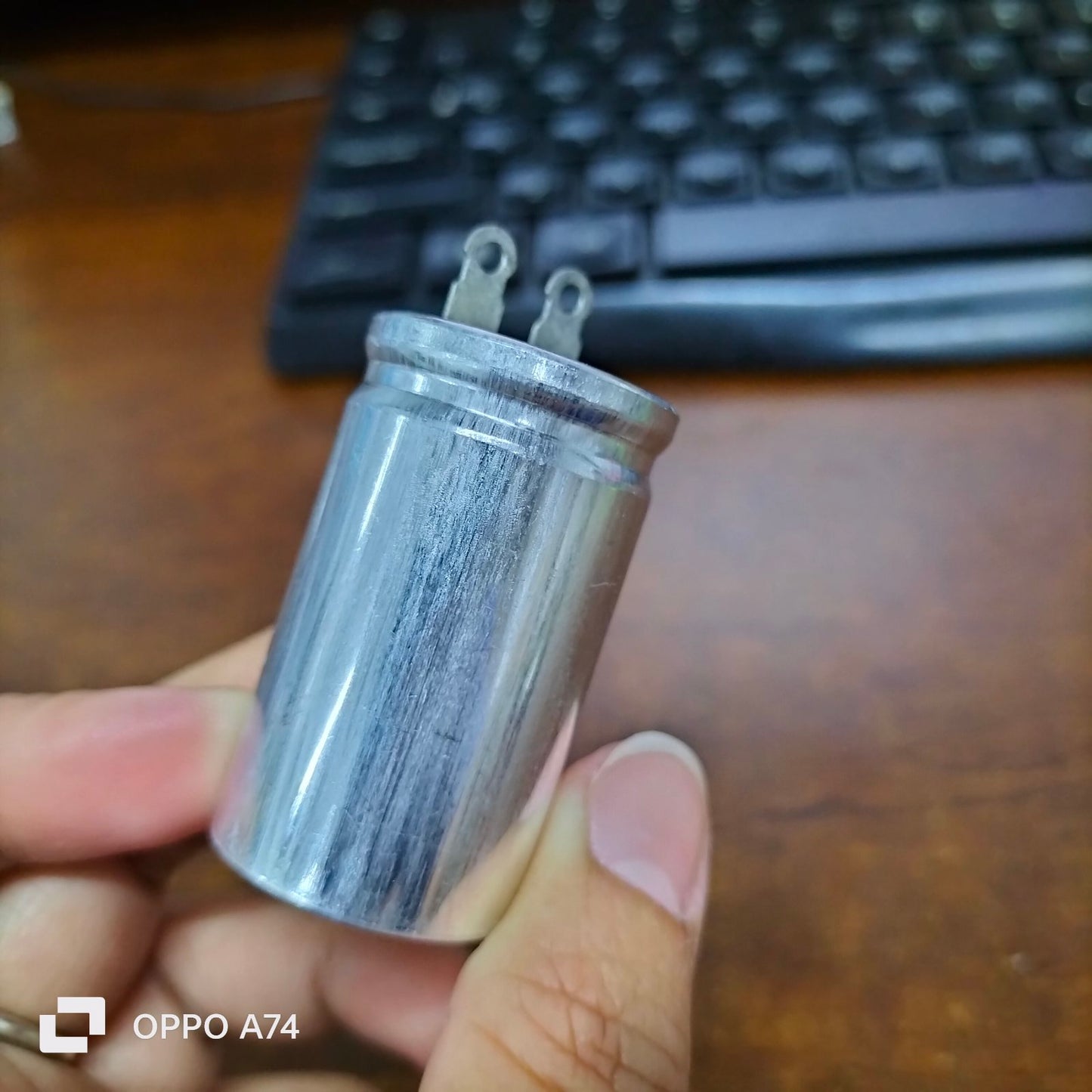 1.7UF motor running capacitor electrical circuitry part from Japan held in hand against keyboard background