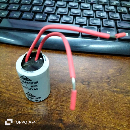 DRE 1MFD 250V AC motor running capacitor with red wires on a wooden surface
