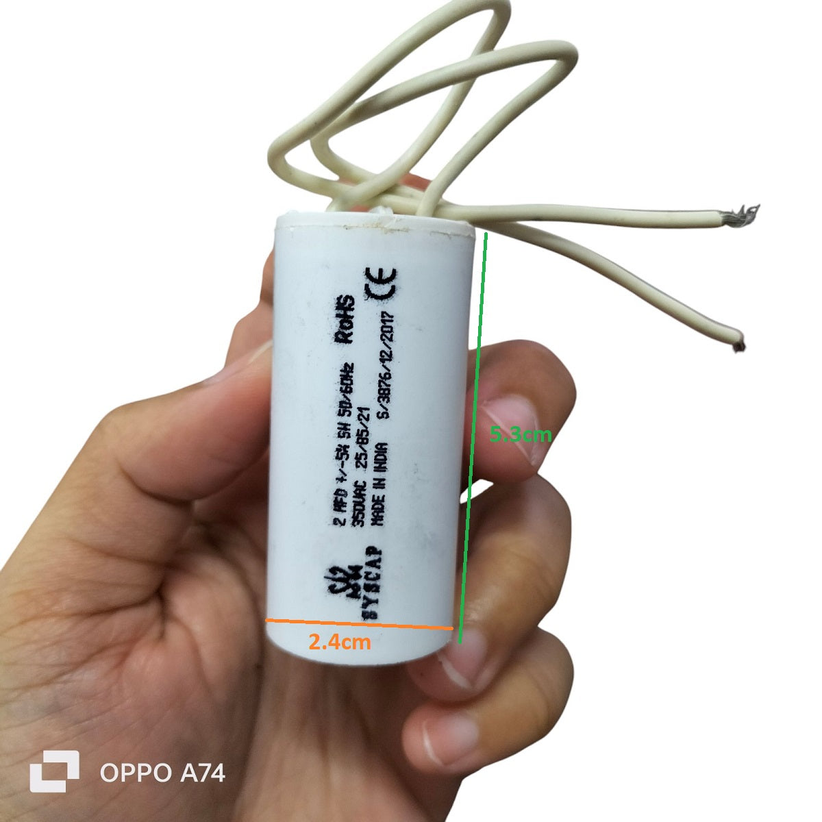 Syscap 2MFD 350V AC Running Capacitor held in hand with white wires for electrical circuitry