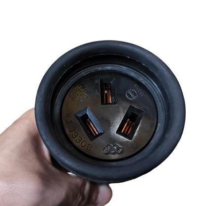 Close-up of a black electrical plug held by a hand on a white background