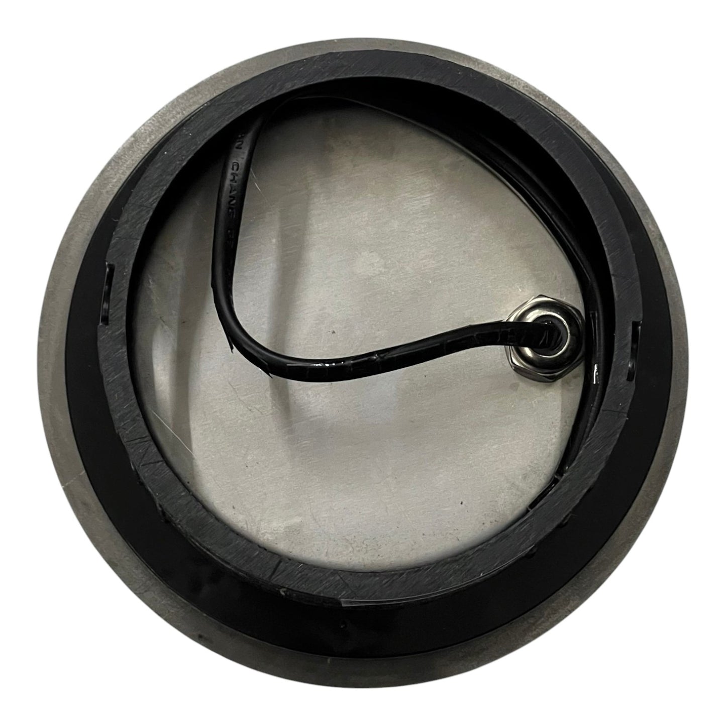 Round metal component with a black handle on a white background