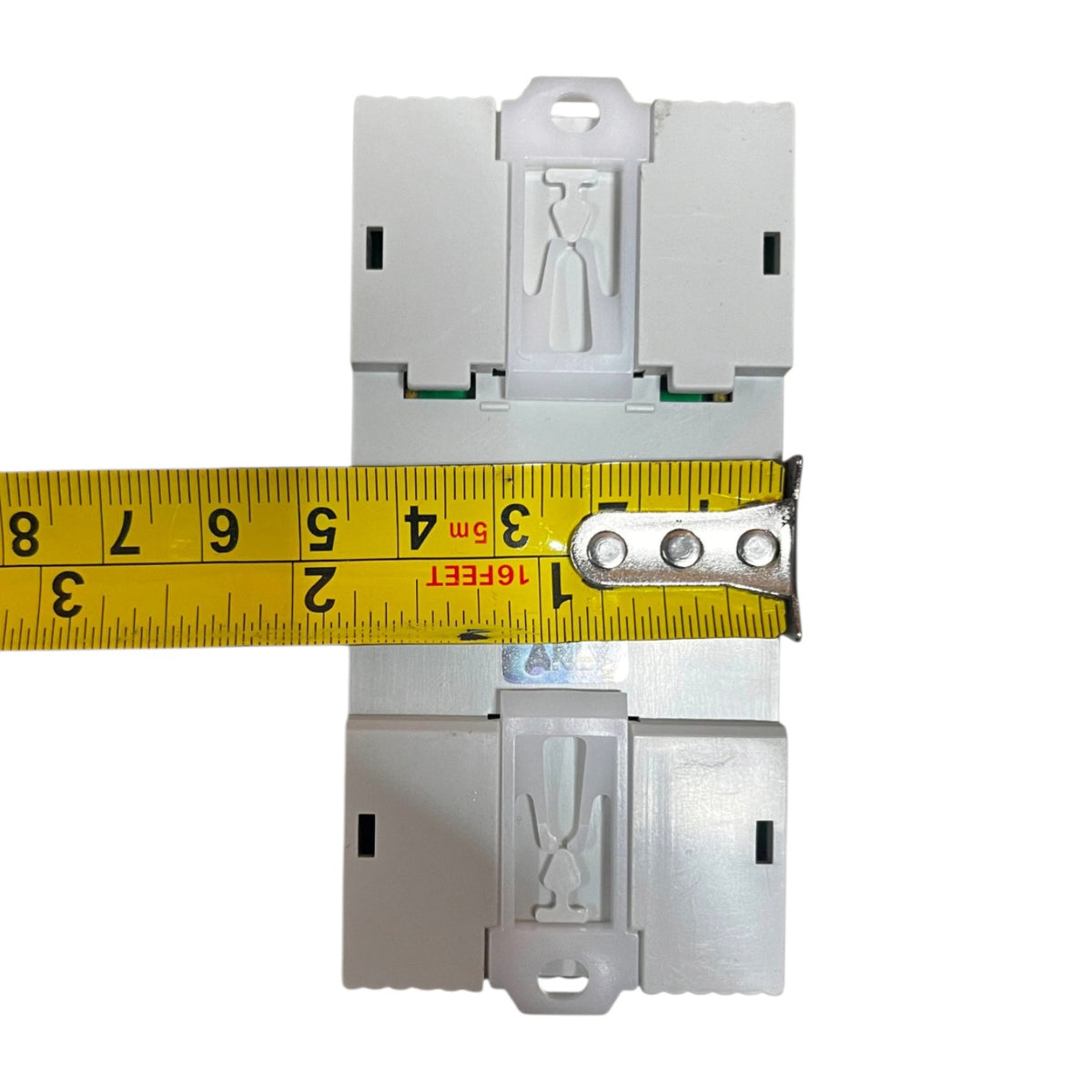 A white plastic electrical terminal block or connector component shown from the front, with a yellow tape measure laid horizontally across the middle to indicate its width. The background is solid white.