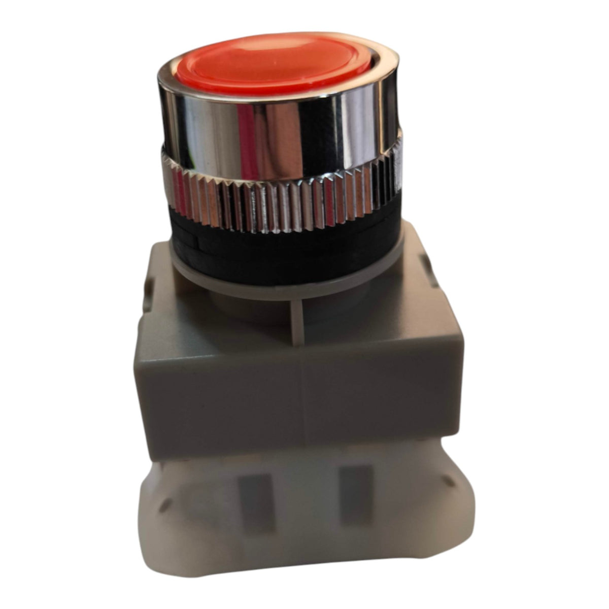 A heavy-duty industrial push button with a red top, a shiny chrome silver bezel, a black ribbed collar, and a gray plastic base, isolated on a white background.