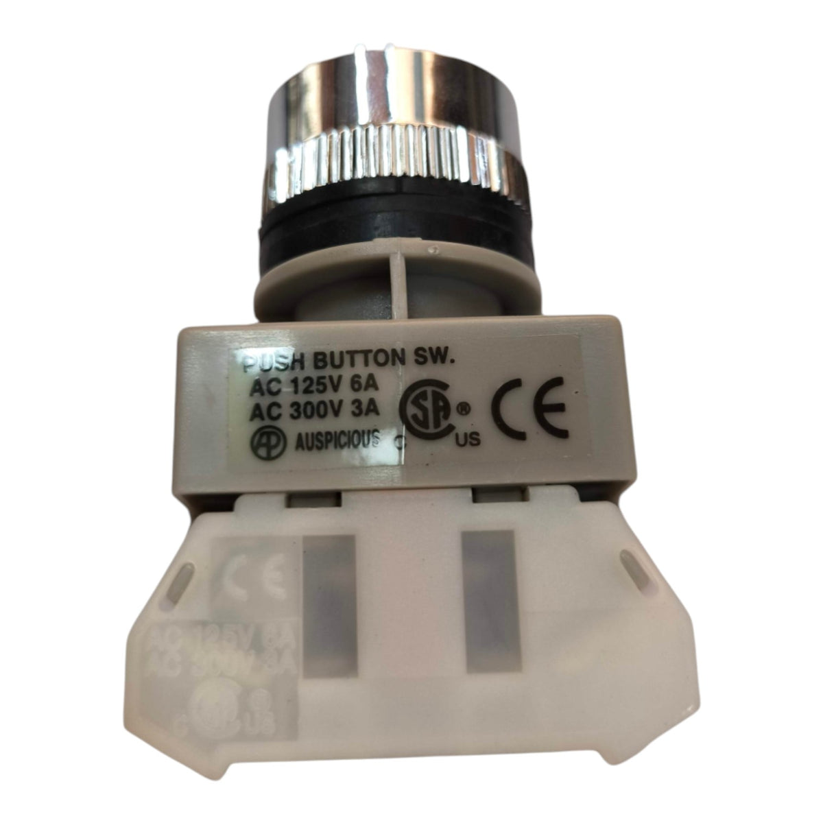 A small industrial push button switch assembly with a silver metal top, black ring, white plastic housing, and printed technical specifications on the side.