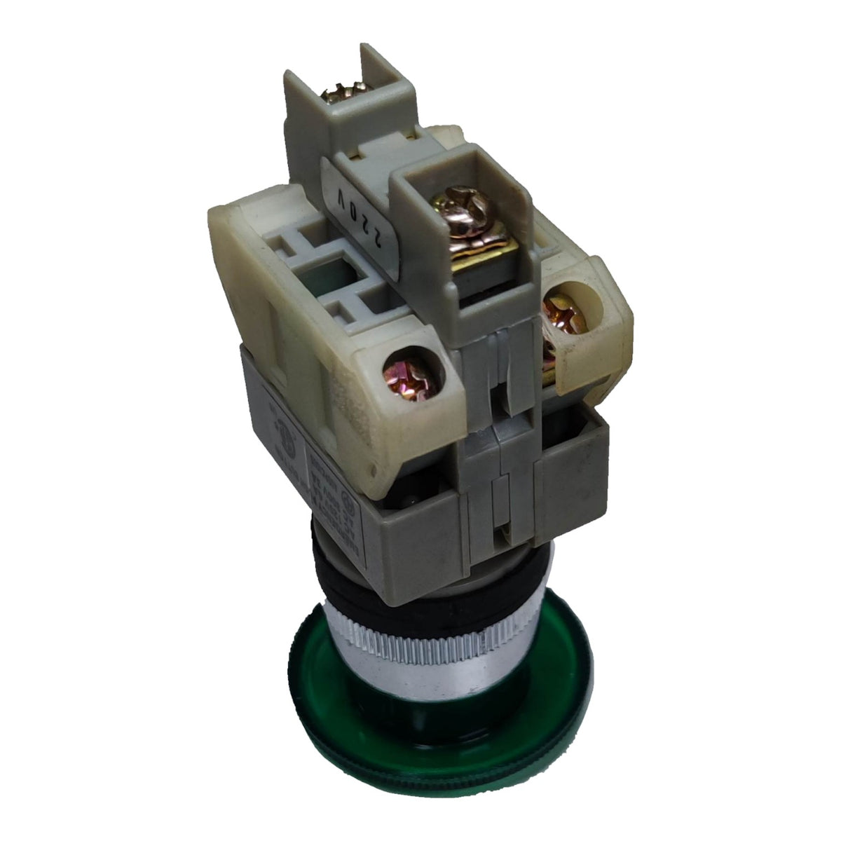 An industrial electrical push-button switch module with a gray plastic housing, beige terminal blocks, copper-colored screws, a silver knurled ring, and a green circular base, isolated on a white background.