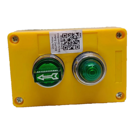 A yellow industrial control panel housing two push buttons: a green directional button with a white arrow and a green illuminated button. A white label with a QR code and technical specifications is affixed to the top.