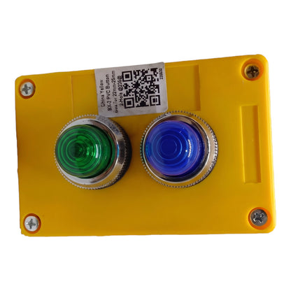 A yellow industrial control panel featuring two large push buttons: a green button on the left and a blue button on the right, both with silver metal bezels. A white sticker with a QR code is affixed near the top center.