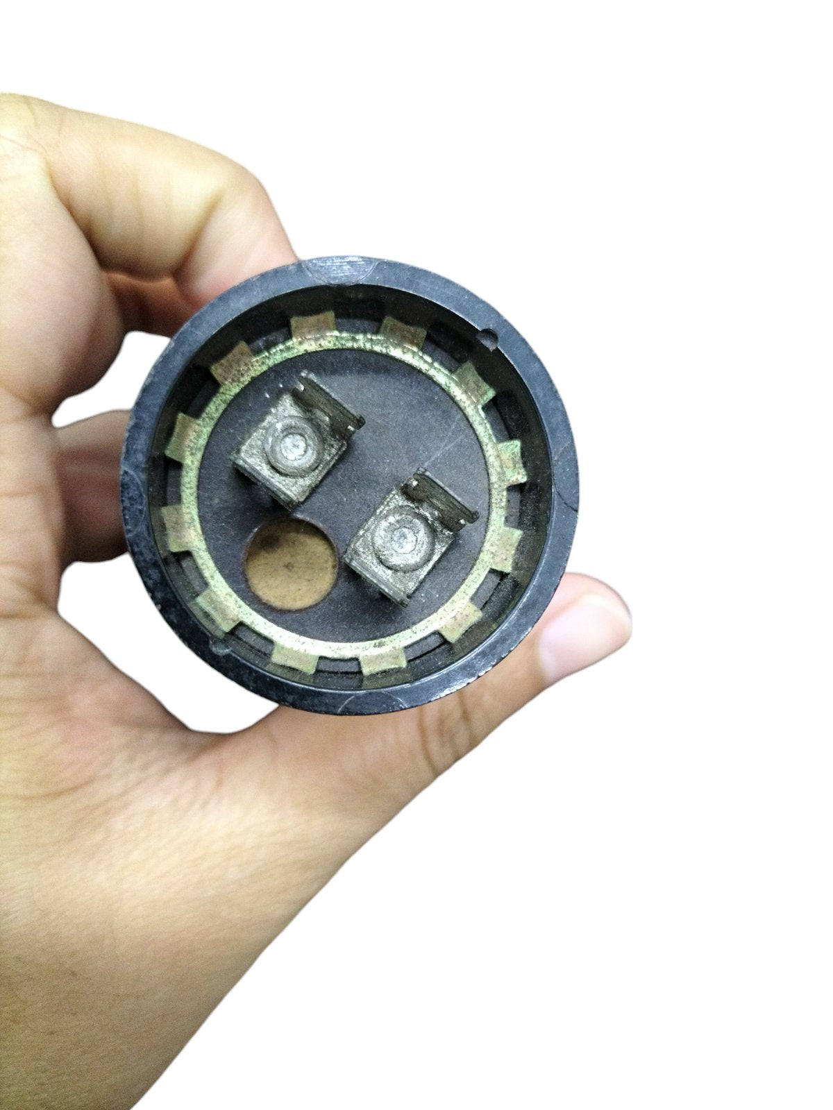 Hand holding a BMI 645-774 UF motor capacitor 125V electrical component with two metal terminals