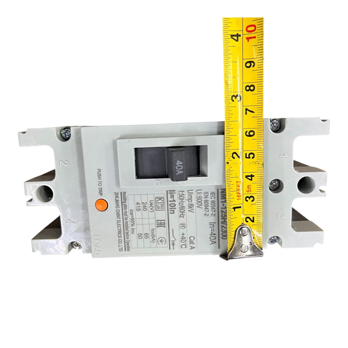A gray electrical circuit breaker shown on a white background with a yellow tape measure standing vertically next to it for scale.