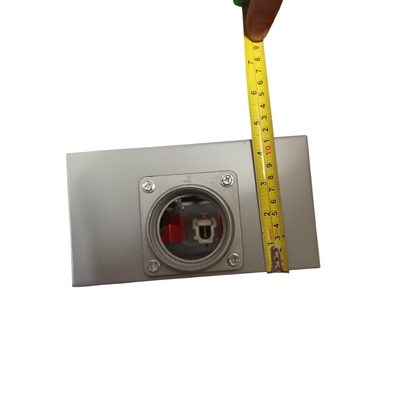 Metal electrical outlet with a tape measure for scale on a white background