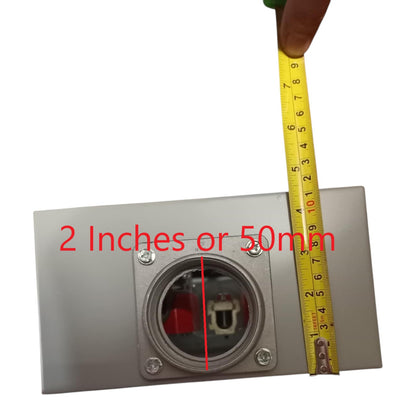Metallic electrical outlet with a tape measure for scale on a white background