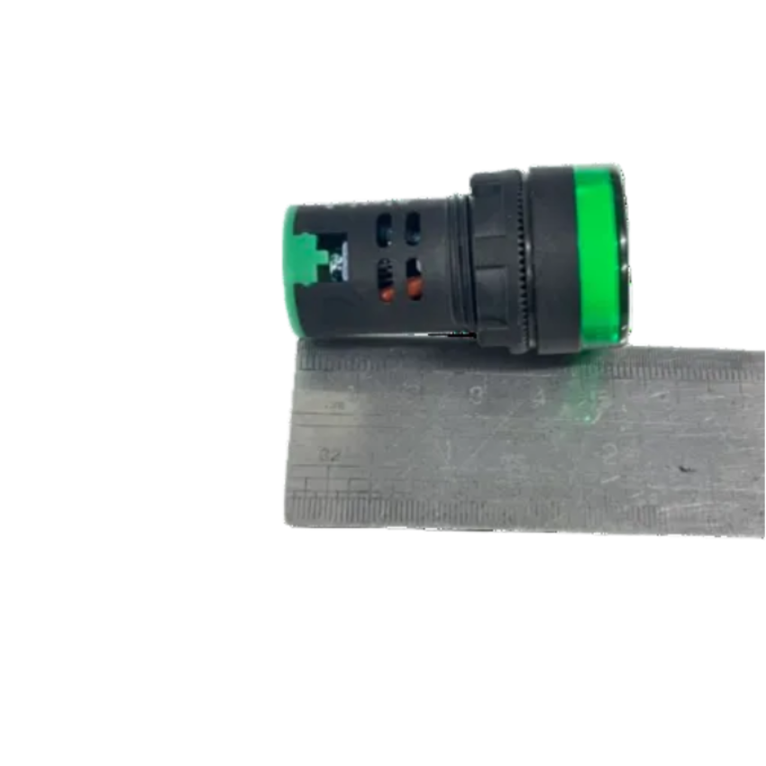A small cylindrical black plastic component with bright green end caps, shown resting horizontally on top of a metal ruler against a plain white background.