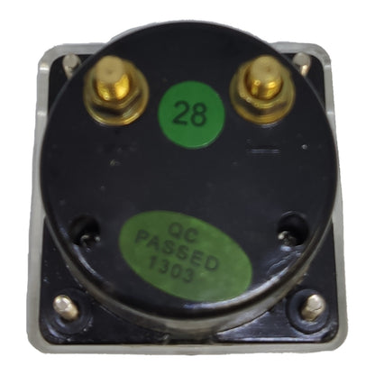 A square metal electrical component with a black circular top plate, two gold screw terminals, and green stickers reading '28' and 'QC PASSED 1303'.