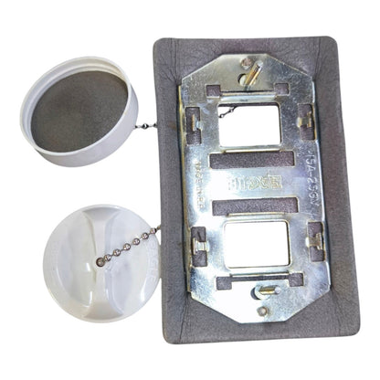 A metal electrical outlet cover plate with a gray textured surround, shown with two white plastic caps and a ball chain on a plain white background.