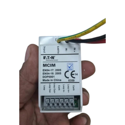 A hand holding an MCIM electrical terminal block module with three wires connected, shown against a plain white background.