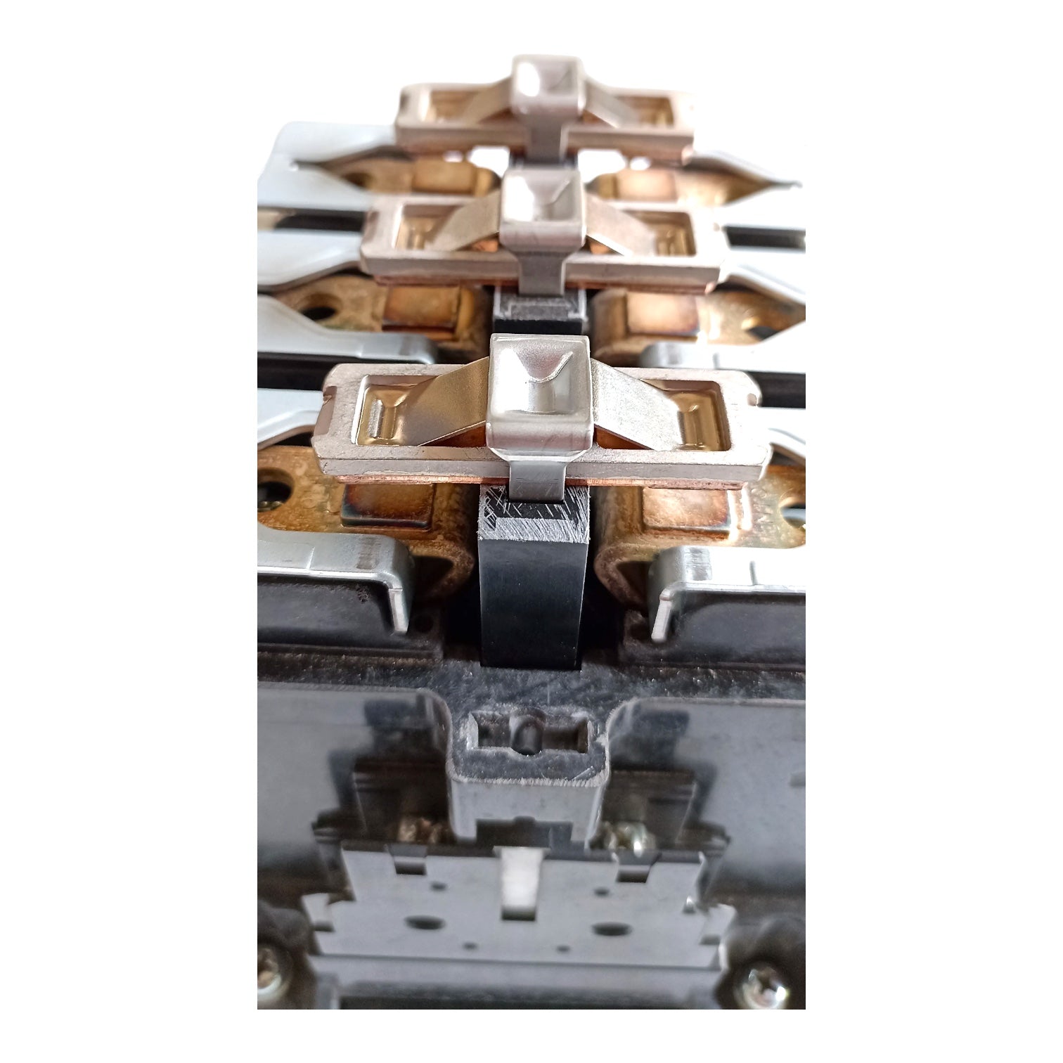 A close-up of a multi-terminal electrical connector or relay component showing copper-colored contacts, silver metal terminals, and a black insulating block, isolated on a white background.