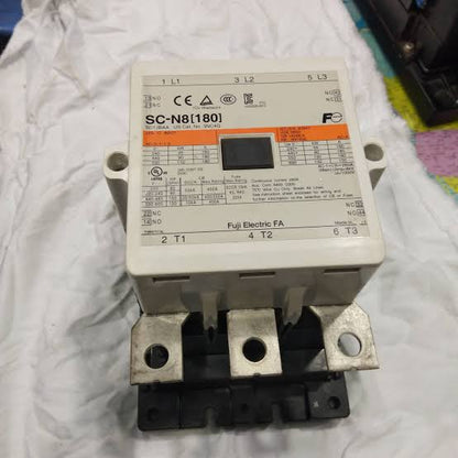 A Fuji Electric contactor, model SC-N8[1801], with a beige plastic housing, metal terminal bars, and a black base, resting on a wrinkled white cloth.