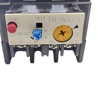 A close-up of an electrical contactor terminal block, model TR-N3/3, featuring a beige front panel with a red test button, a blue reset switch, and a yellow adjustment dial, set against a plain white background.