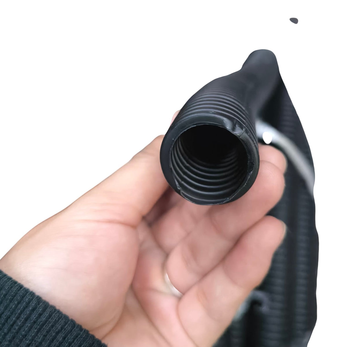 A close-up of a hand holding a black corrugated hose or tube connector against a plain white background.