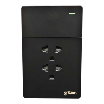 A black Gräzen dual UK wall outlet power strip with a small green LED indicator light on the top right, shown against a plain white background.
