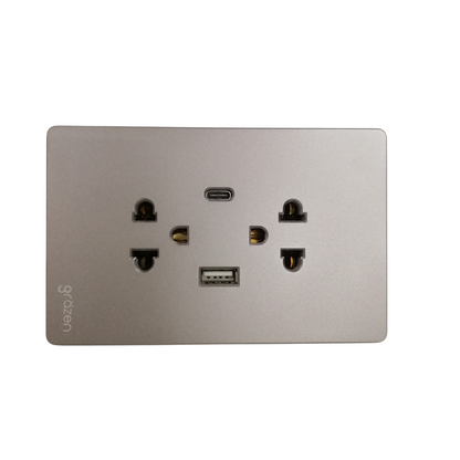 A brushed silver metal wall outlet panel featuring a USB-C port, a USB-A port, and dual US-style electrical outlets. The brand name 'gyozen' is printed vertically on the lower left.