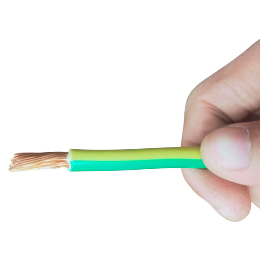 A close-up of a hand holding a cut electrical wire cable with green and yellow outer insulation and exposed copper strands on a white background.
