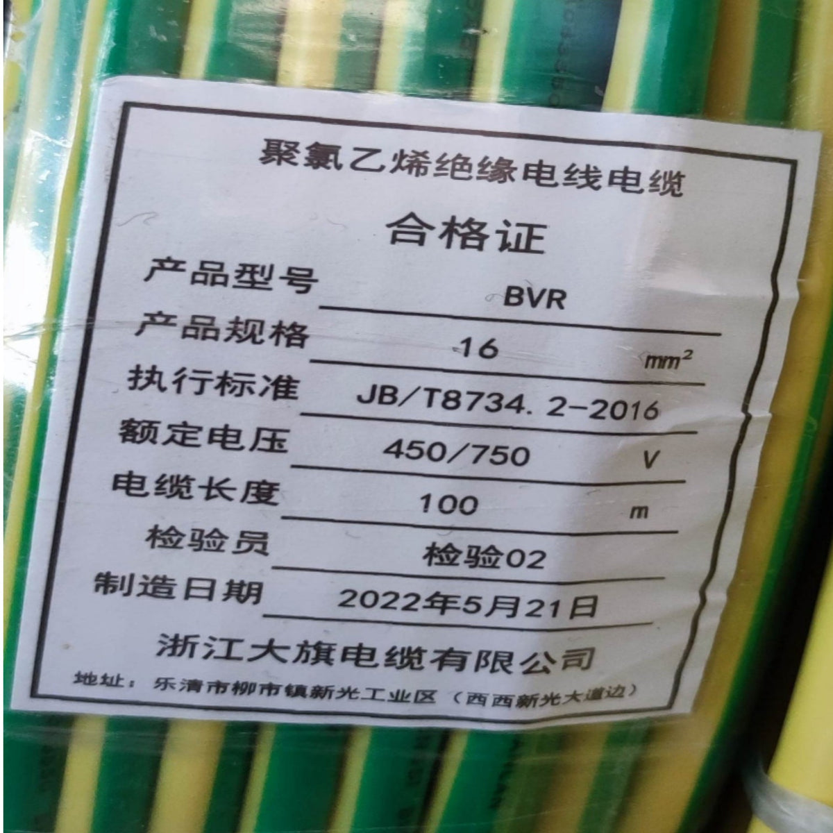 A close-up of a green and yellow striped bundle of PVC insulated wire cable with a white paper certification label showing Chinese text and specifications.