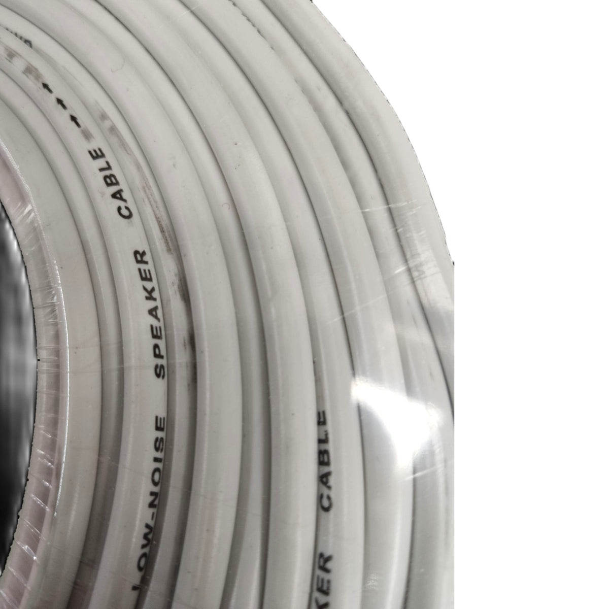 A close-up of a coiled white speaker cable wrapped in clear protective plastic, with black printed text reading 'LOW-NOISE SPEAKER CABLE'.