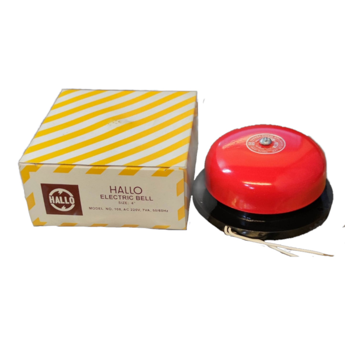A red and black HALLO electric bell next to its original box, which features a yellow and white diagonal striped pattern.