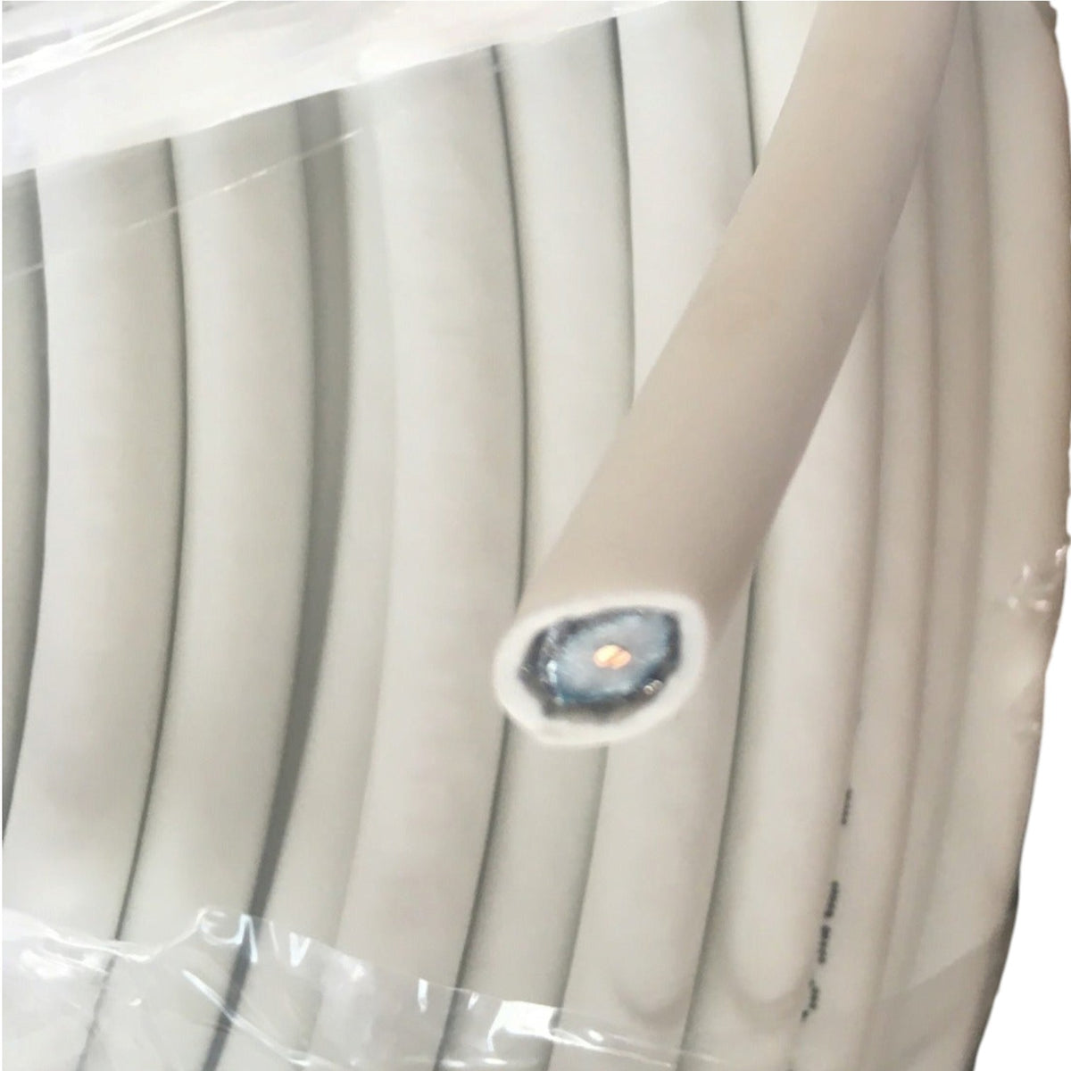 A close-up of a coiled light beige or off-white cable wrapped in clear plastic, with one end exposed showing a blue-gray inner core and a small gold center.