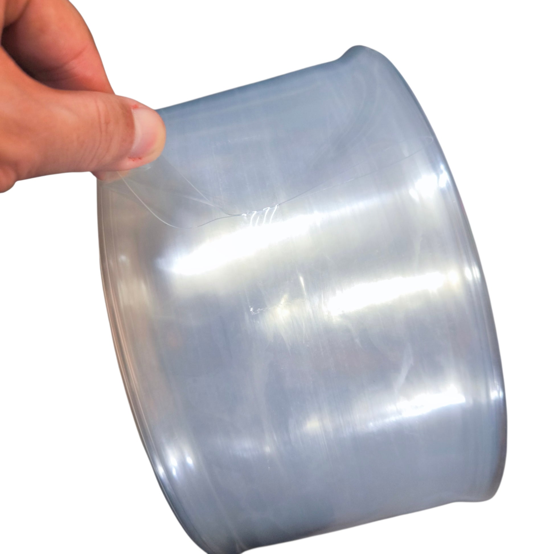 Person holding a roll of clear plastic wrap against a white background
