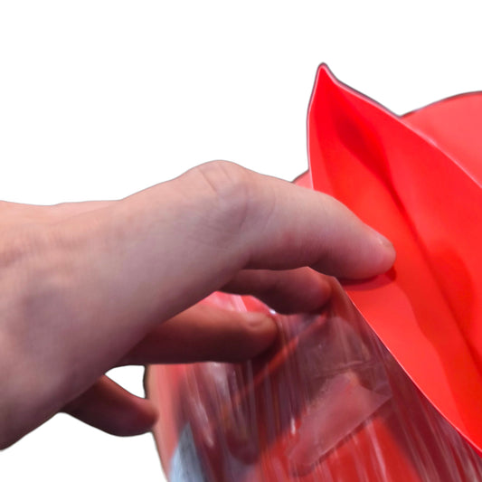 Hand holding a red plastic bag against a white background