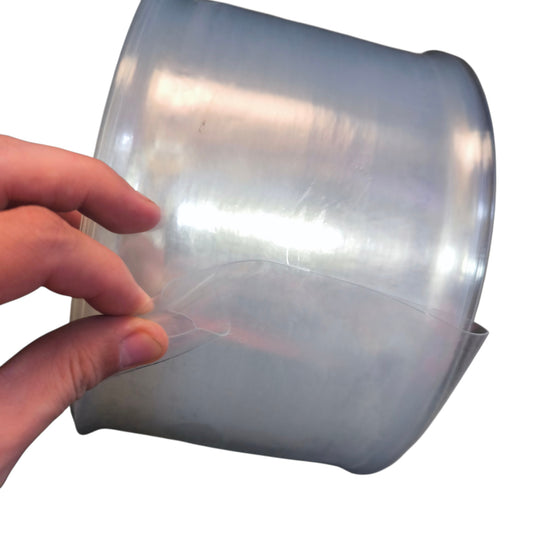 Hand holding a roll of clear plastic wrap against a white background