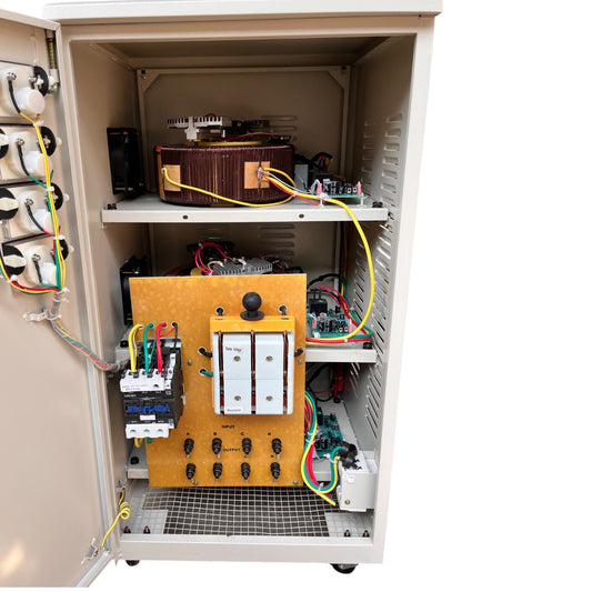Open industrial electrical cabinet showing internal components including a yellow control panel, wiring, circuit breakers, and transformers on metal shelves against a white background.
