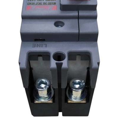 A close-up of a dark gray electrical circuit breaker component with metal terminal screws and a small red label on a white background.