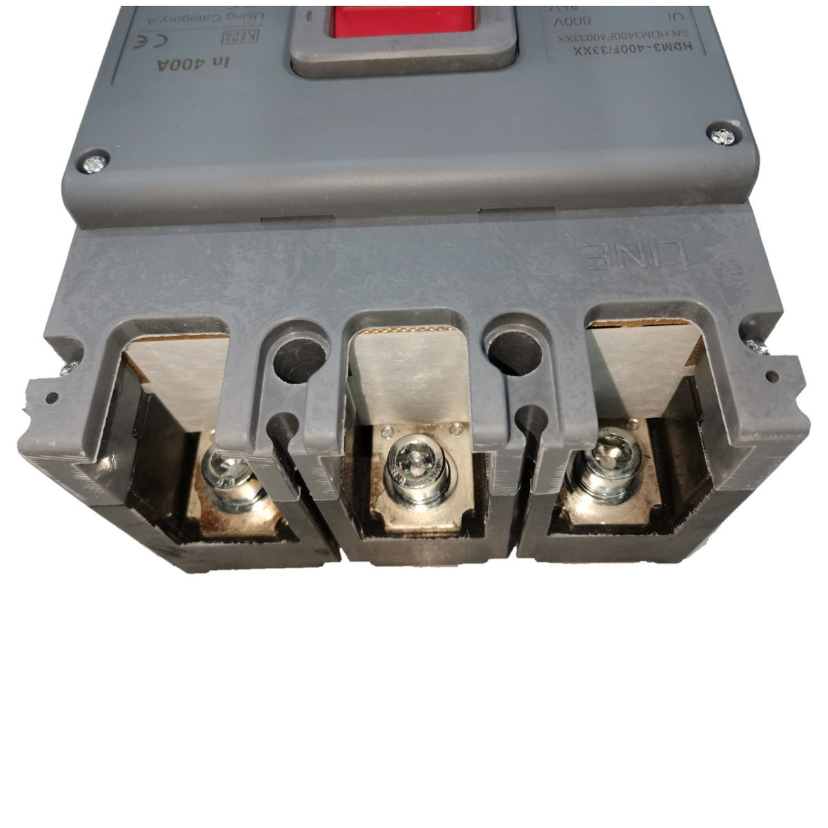 A close-up of an industrial electrical component, likely a circuit breaker or fuse holder, with a gray plastic housing, three metal terminal blocks, and a red switch tab on top.