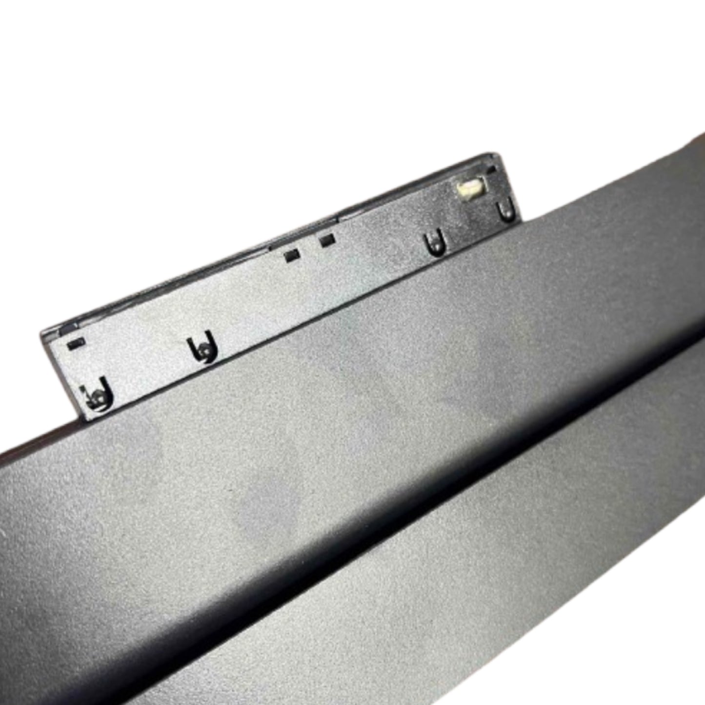 Close-up of a dark gray or black metal panel with a small mounting bracket attached, photographed on a plain white background.