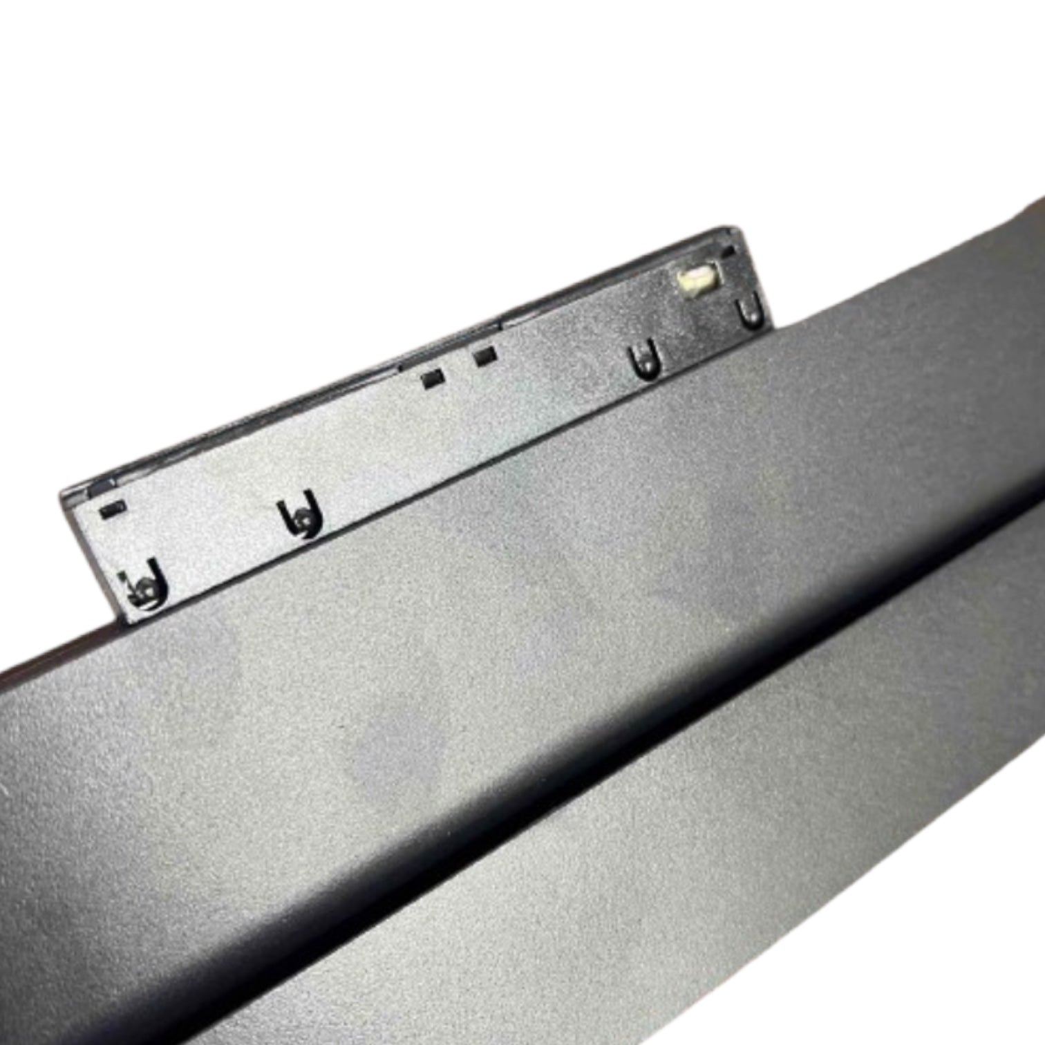 Close-up of a dark gray or black metal panel with a small mounting bracket attached, photographed on a plain white background.