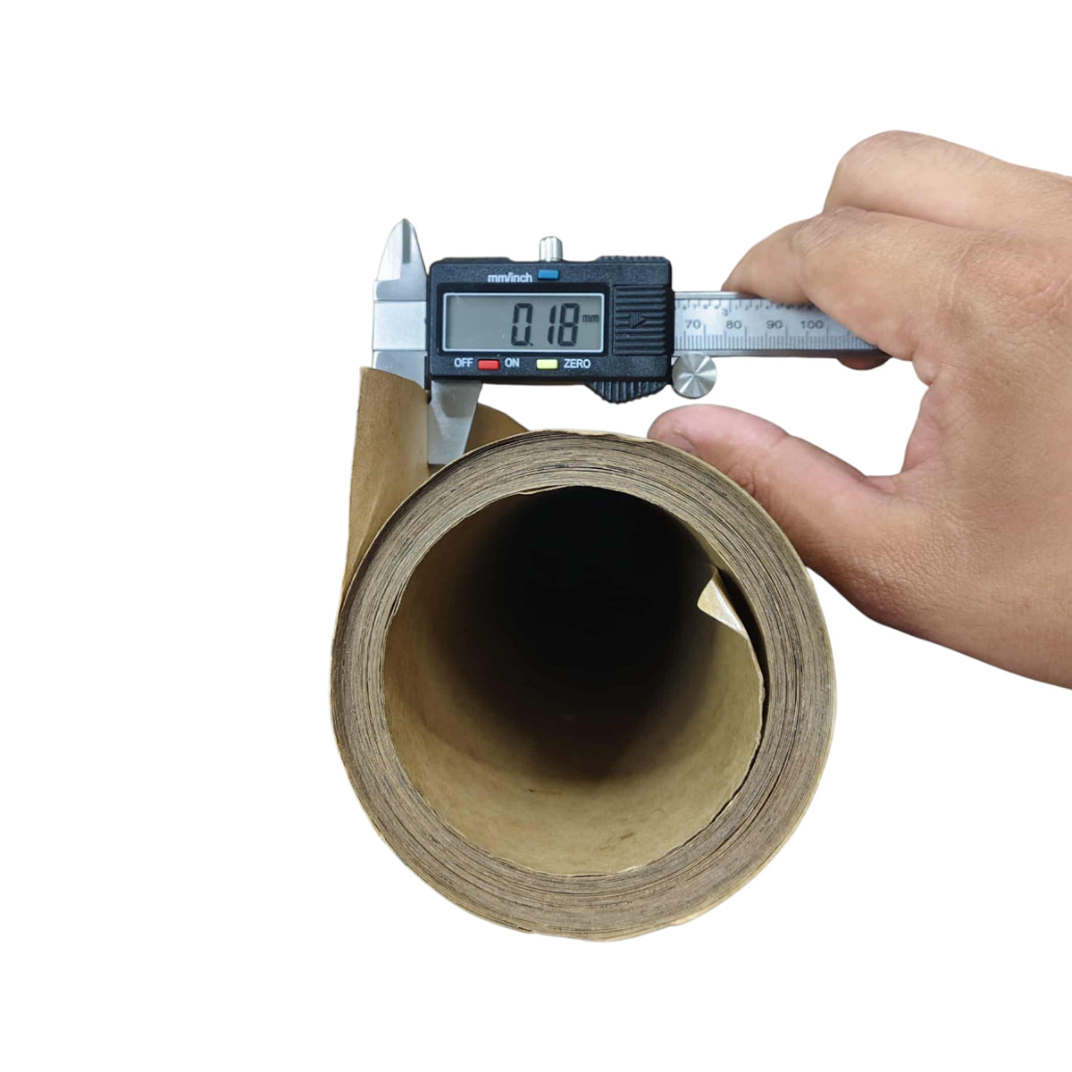 Roll of cardboard with a digital caliper measuring its thickness on a white background