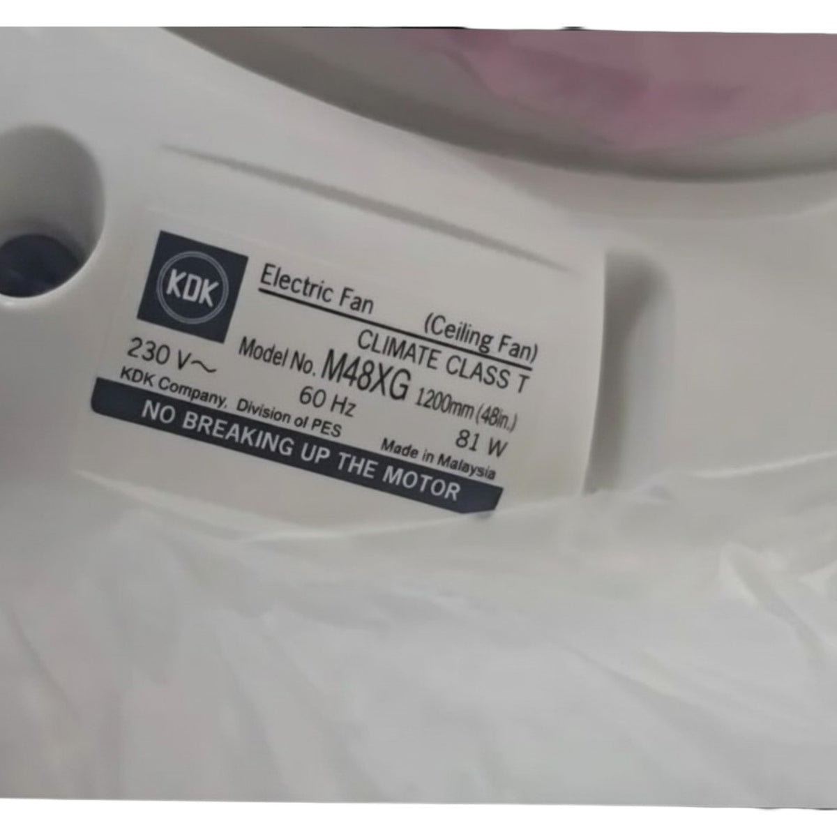 A close-up of a white ceiling fan motor housing with a white product label. The label features the KDK brand logo and text identifying it as an Electric Fan, Model M48XG, with specifications including 230V, 60Hz, and 81W.